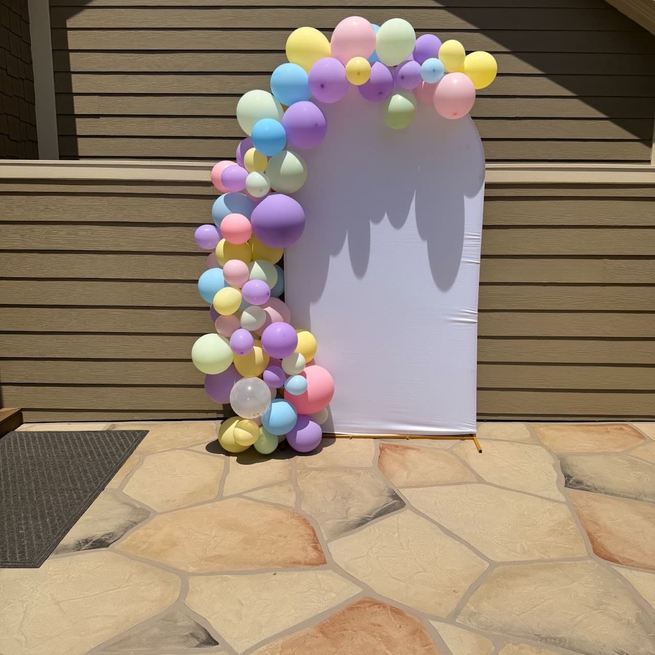 Pastel rainbow organic balloon arch in front of a white backdrop