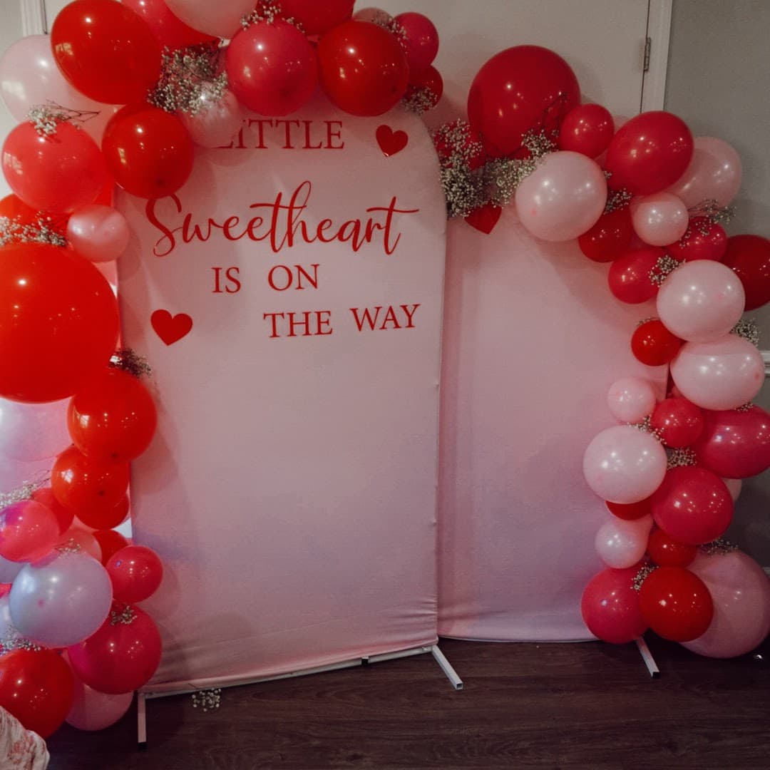 Red and pink balloon backdrop for a “Little Sweetheart” baby announcement