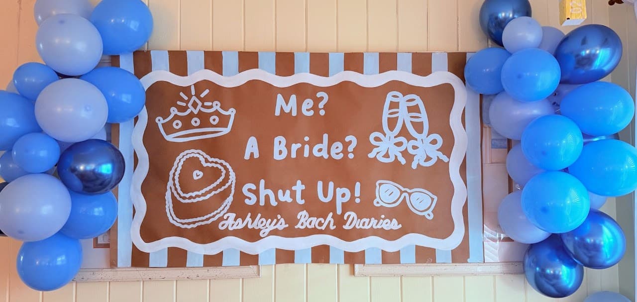 Blue balloon garland framing a bachelorette weekend sign